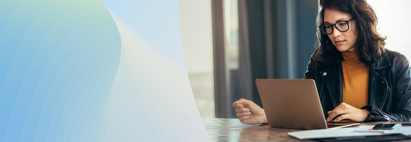 A person sitting indoors at a desk with a laptop.