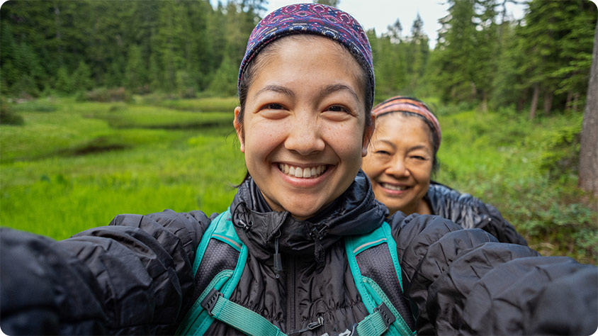 Two smiling women hiking outdoors.